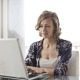 Self employed woman, smiling filling in her pay stub generator templates on a laptop